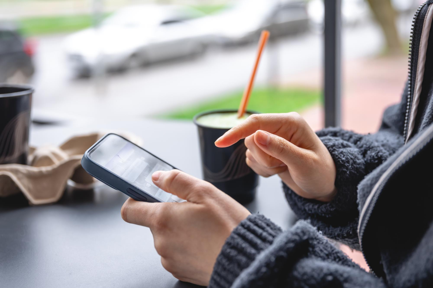 a guy is sitting at a table and using a phone